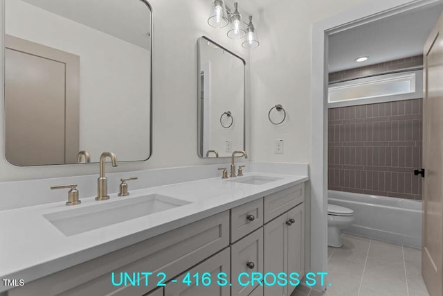 bathroom with double vanity, toilet, tile patterned floors, and a sink