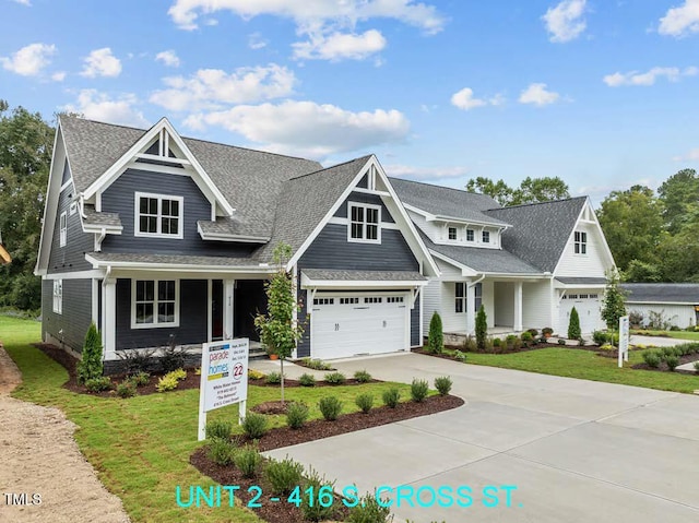 view of front of house with a porch, driveway, a front yard, and a garage