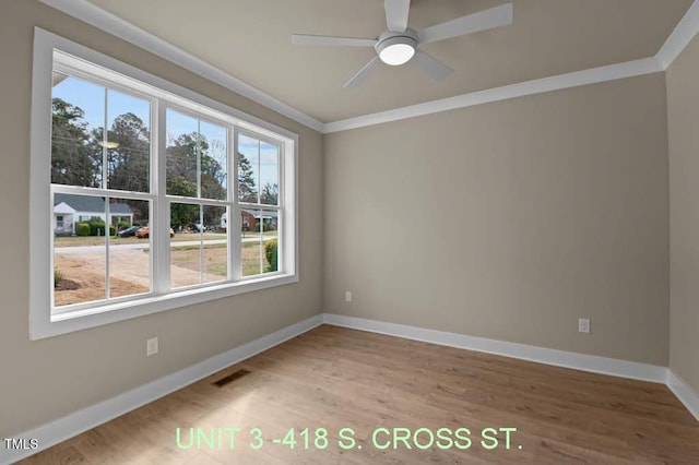 unfurnished room featuring baseboards, visible vents, ornamental molding, and wood finished floors