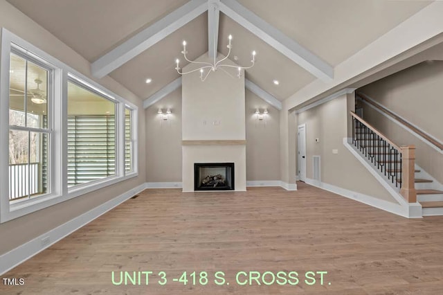 unfurnished living room with visible vents, a fireplace, wood finished floors, stairway, and lofted ceiling with beams