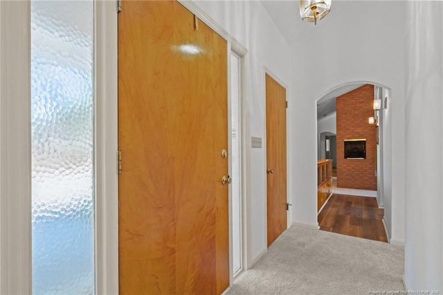 hallway featuring carpet, baseboards, and arched walkways