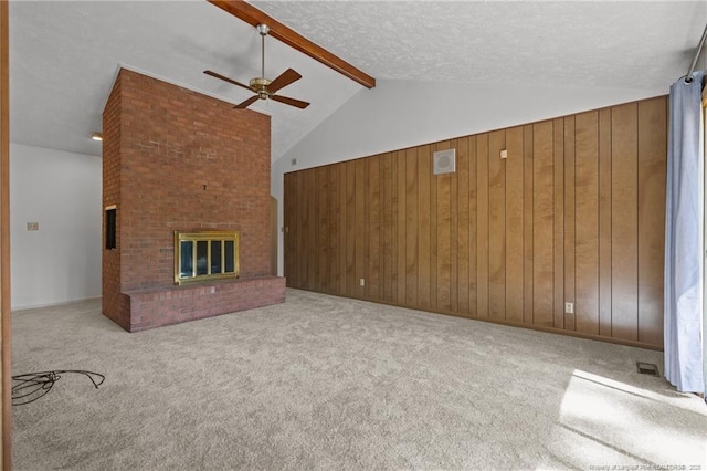 unfurnished living room with a ceiling fan, a textured ceiling, lofted ceiling with beams, wood walls, and carpet flooring