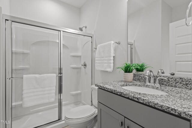 bathroom featuring a stall shower, toilet, and vanity