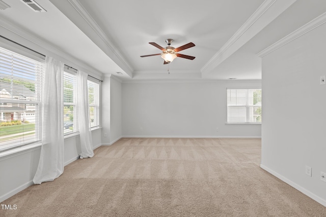 empty room with light carpet, a raised ceiling, ornamental molding, ceiling fan, and baseboards
