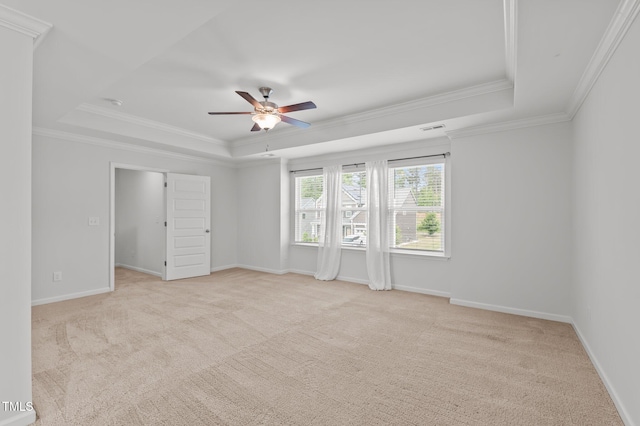 unfurnished bedroom with a tray ceiling, crown molding, light colored carpet, baseboards, and a ceiling fan