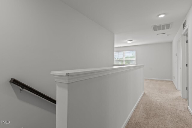 hallway with an upstairs landing, light colored carpet, and baseboards