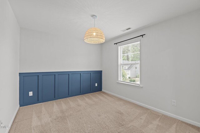 unfurnished room with carpet, a wainscoted wall, and a decorative wall