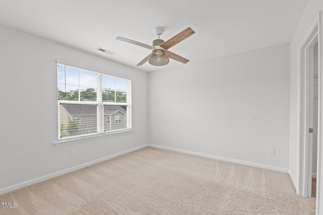carpeted spare room with a ceiling fan and baseboards