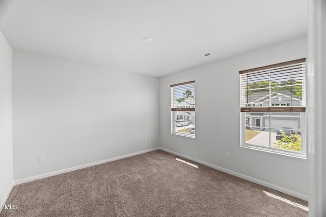 carpeted spare room featuring visible vents and baseboards