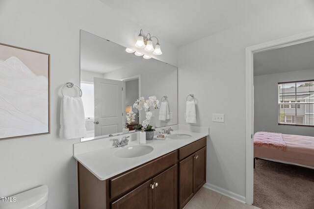 bathroom featuring tile patterned floors, toilet, double vanity, and a sink