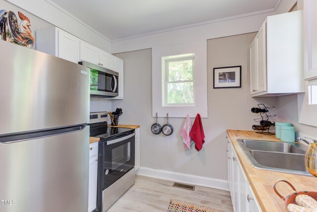 919 Orient St, Durham, NC 27701 - kitchen with a sink, wooden counters, light wood-style flooring, white cabinets, and appliances with stainless steel finishes