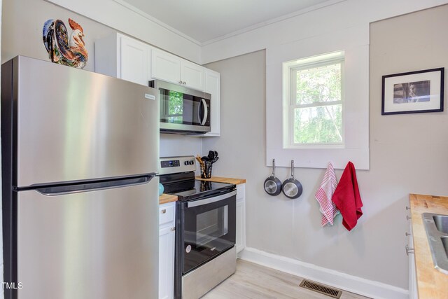 919 Orient St, Durham, NC 27701 - kitchen featuring wood counters, light wood-type flooring, white cabinetry, appliances with stainless steel finishes, and visible vents