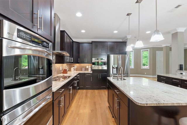 120 Wood Lake Dr, Fuquay Varina, NC 27526 - kitchen with light wood-type flooring, crown molding, light stone countertops, an island with sink, and appliances with stainless steel finishes