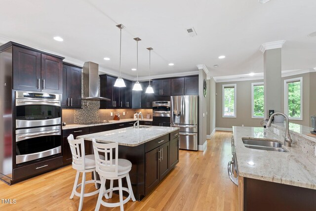 120 Wood Lake Dr, Fuquay Varina, NC 27526 - kitchen with appliances with stainless steel finishes, ornamental molding, a sink, wall chimney exhaust hood, and a center island with sink