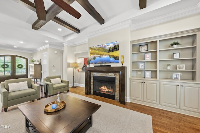 living room with ornamental molding, beam ceiling, a stone fireplace, light wood-type flooring, and recessed lighting