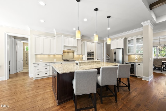 kitchen featuring a breakfast bar area, beverage cooler, stainless steel appliances, backsplash, and ornamental molding