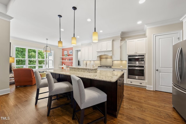 kitchen with ornamental molding, white cabinetry, appliances with stainless steel finishes, and light stone countertops