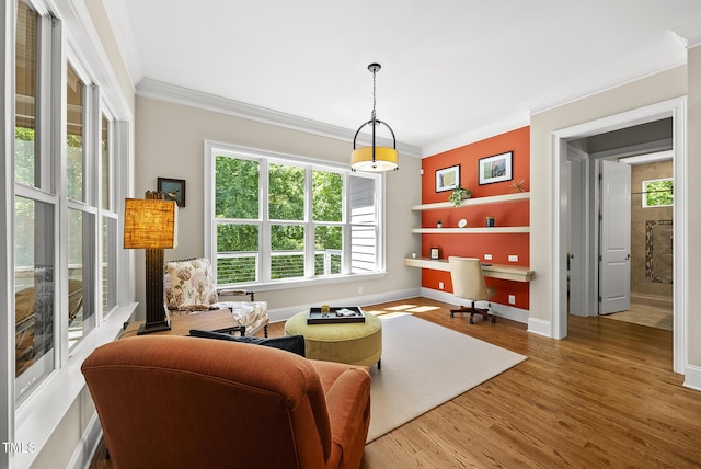 sitting room with crown molding, baseboards, a healthy amount of sunlight, and wood finished floors