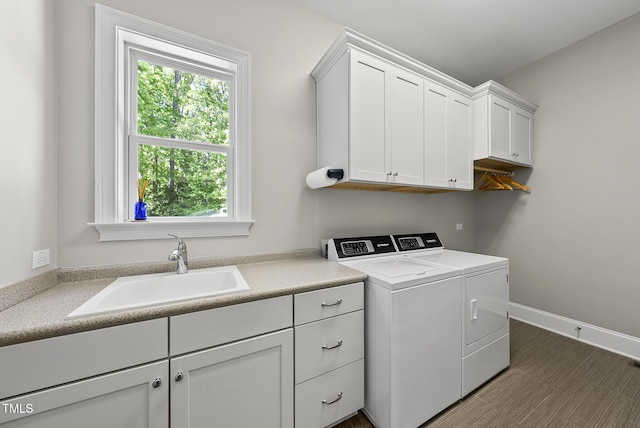 clothes washing area featuring a sink, baseboards, cabinet space, and washer and dryer