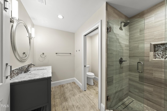 full bathroom featuring vanity, toilet, baseboards, a shower stall, and wood finished floors