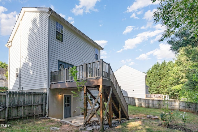 rear view of house with a deck, a fenced backyard, stairs, and an outdoor fire pit