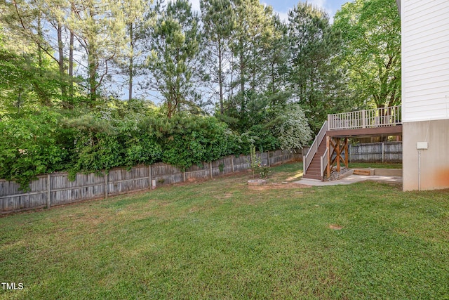view of yard with a fenced backyard, a wooden deck, and stairway