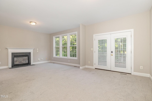 unfurnished living room with french doors, carpet flooring, baseboards, and a fireplace with flush hearth