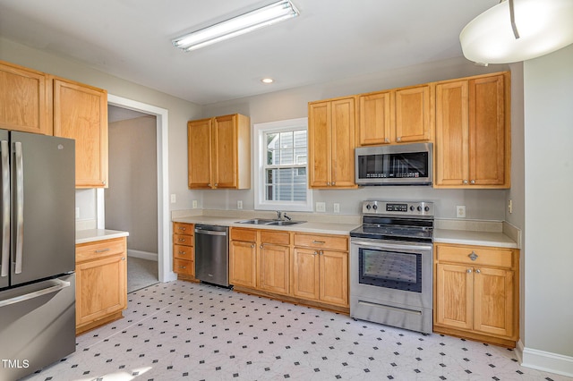 kitchen featuring light countertops, baseboards, appliances with stainless steel finishes, and a sink