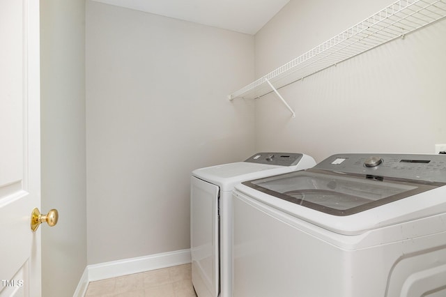 laundry area with light tile patterned floors, laundry area, washing machine and dryer, and baseboards