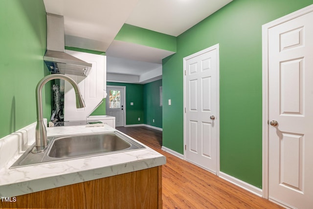 kitchen featuring light countertops, baseboards, a sink, and light wood-type flooring