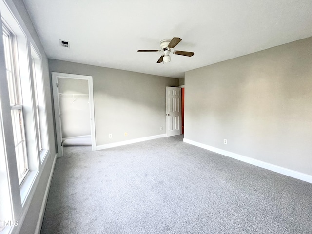 carpeted empty room with a ceiling fan, baseboards, and visible vents
