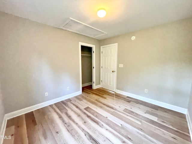 spare room with baseboards, wood finished floors, and attic access