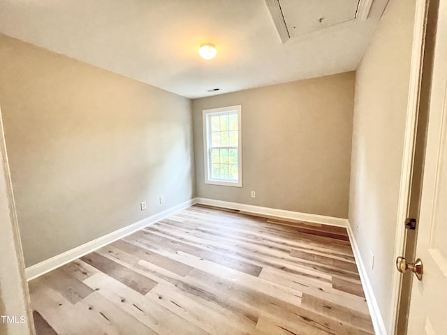 spare room featuring baseboards, attic access, wood finished floors, and visible vents