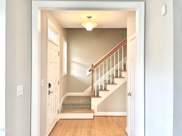 entrance foyer featuring wood-type flooring, baseboards, and stairway
