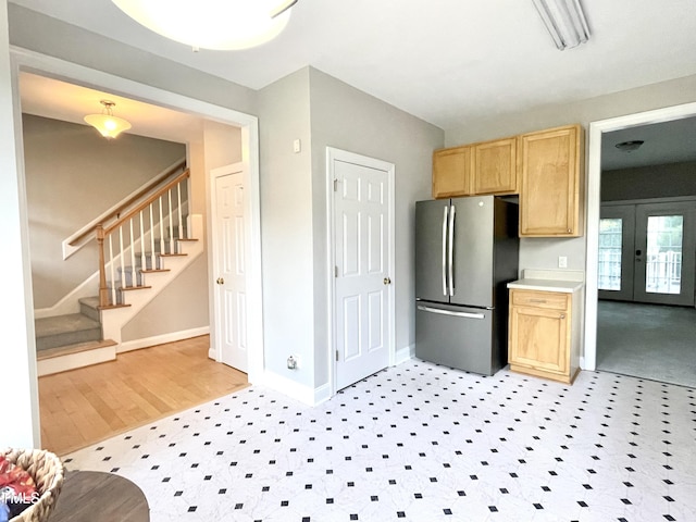 kitchen featuring french doors, light brown cabinetry, light wood-type flooring, baseboards, and freestanding refrigerator
