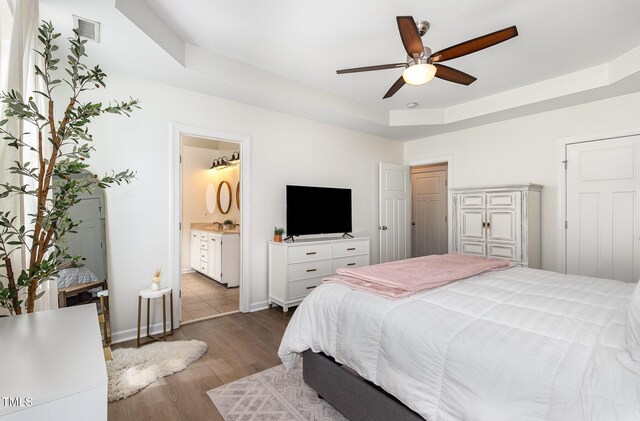 1209 Shasta Daisy Dr, Wake Forest, NC 27587 - bedroom featuring wood finished floors, baseboards, a raised ceiling, ensuite bath, and ceiling fan