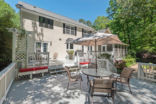 wooden deck featuring outdoor dining space and a sunroom