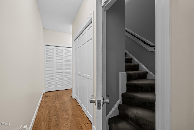 staircase featuring wood finished floors and baseboards