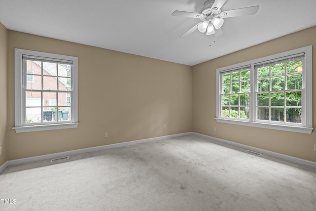 carpeted spare room featuring baseboards and a ceiling fan