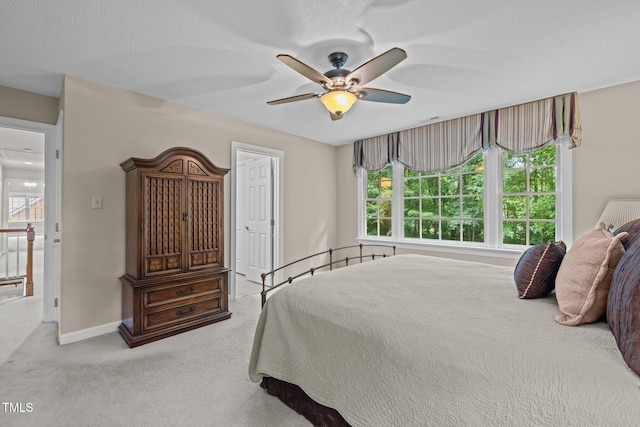 carpeted bedroom featuring multiple windows, baseboards, a ceiling fan, and a textured ceiling