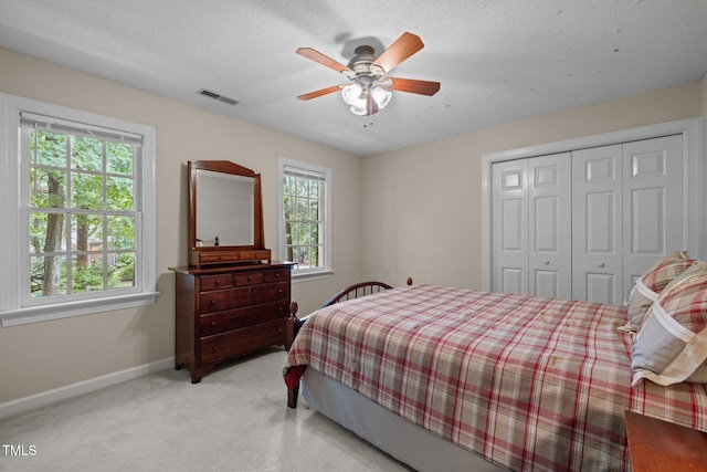 bedroom with multiple windows, baseboards, a closet, and light colored carpet