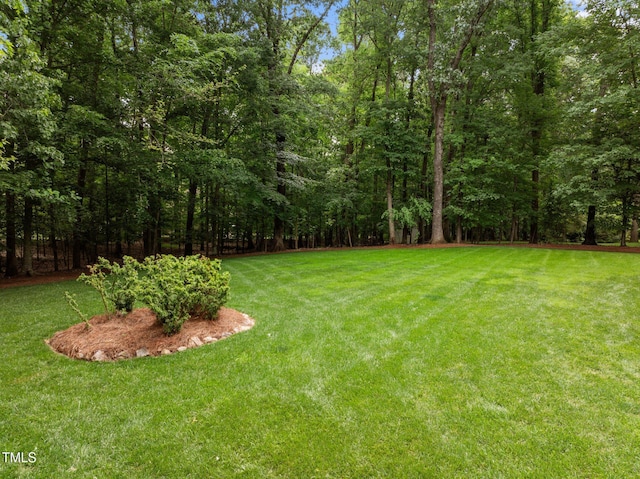 view of grassy yard with a view of trees