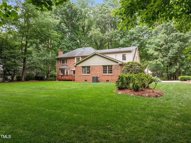 rear view of property featuring crawl space, a deck, brick siding, a chimney, and a yard