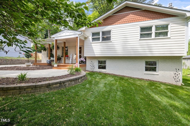 back of house with brick siding, a yard, and a porch
