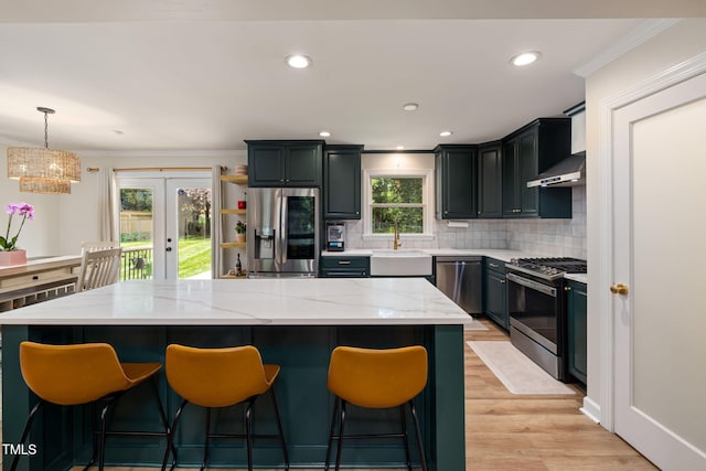kitchen featuring a sink, french doors, stainless steel appliances, light wood finished floors, and backsplash