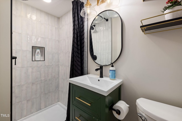 full bathroom featuring a tile shower, toilet, and vanity