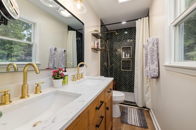 full bath with wood finished floors, a sink, double vanity, and a tile shower