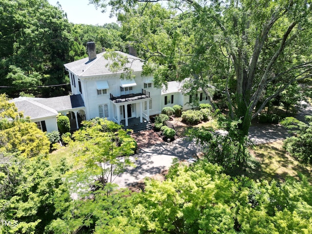 view of front of property with a view of trees, a chimney, roof with shingles, and a deck