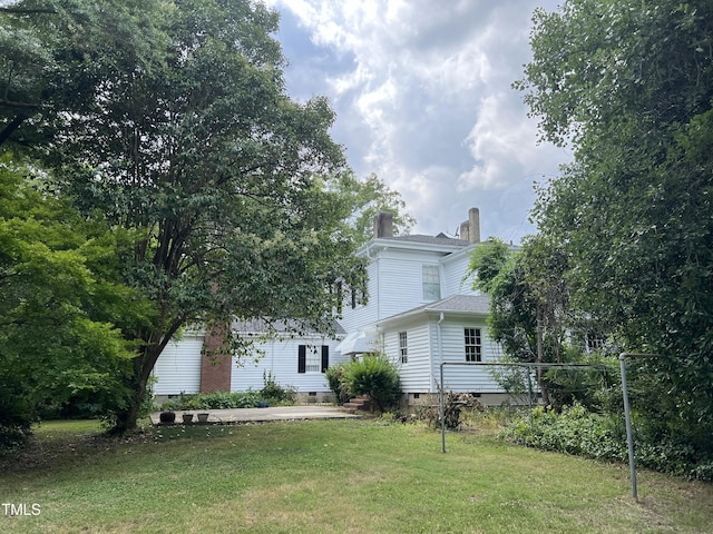rear view of house featuring a chimney, crawl space, and a lawn
