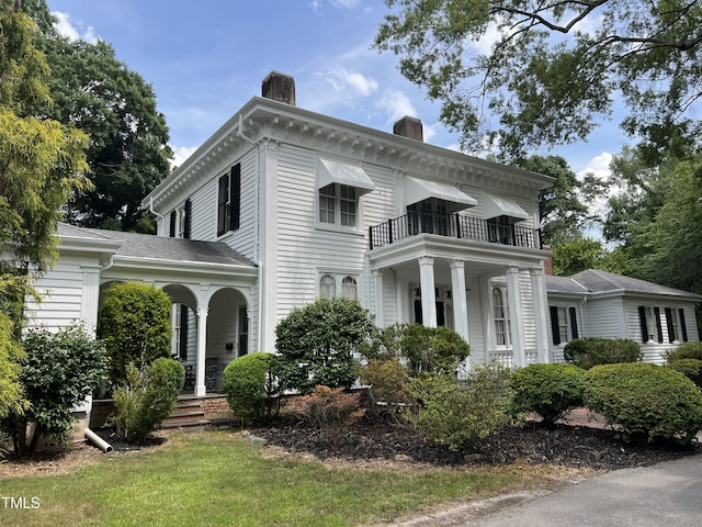 view of front of house with a chimney, a balcony, and covered porch